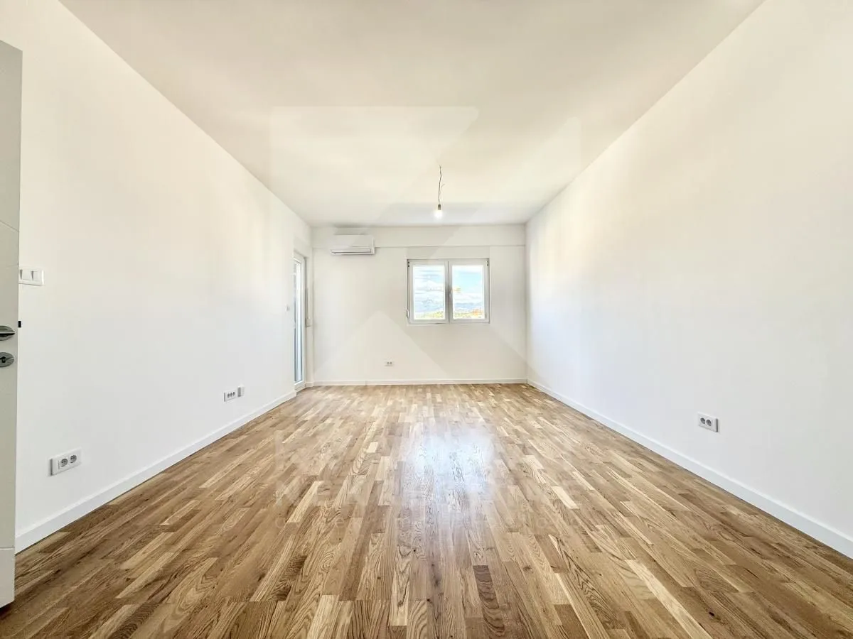 Empty room with white walls, wooden flooring and a window.