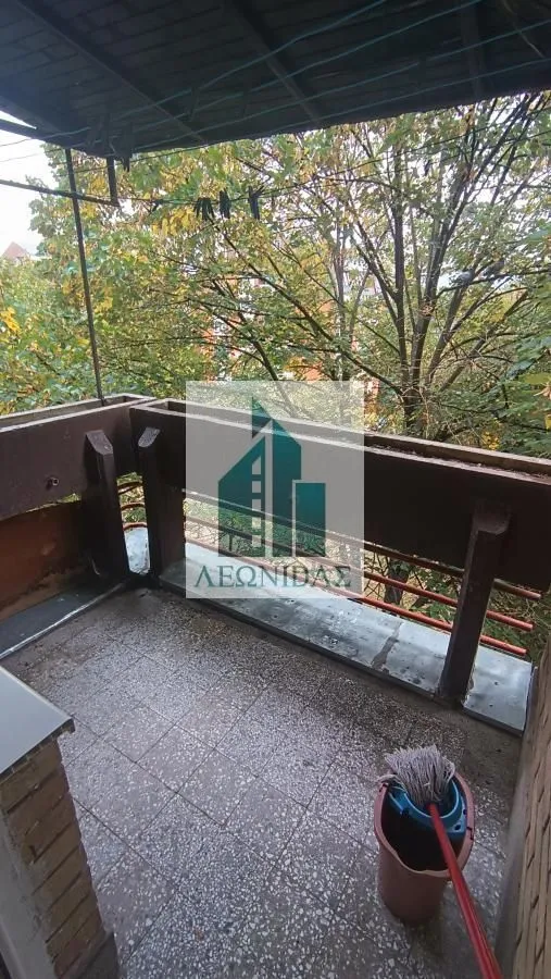 Covered balcony with a view of green trees.