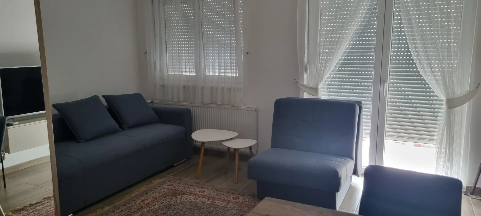 Dnevna soba sa garniturom i prozorima.