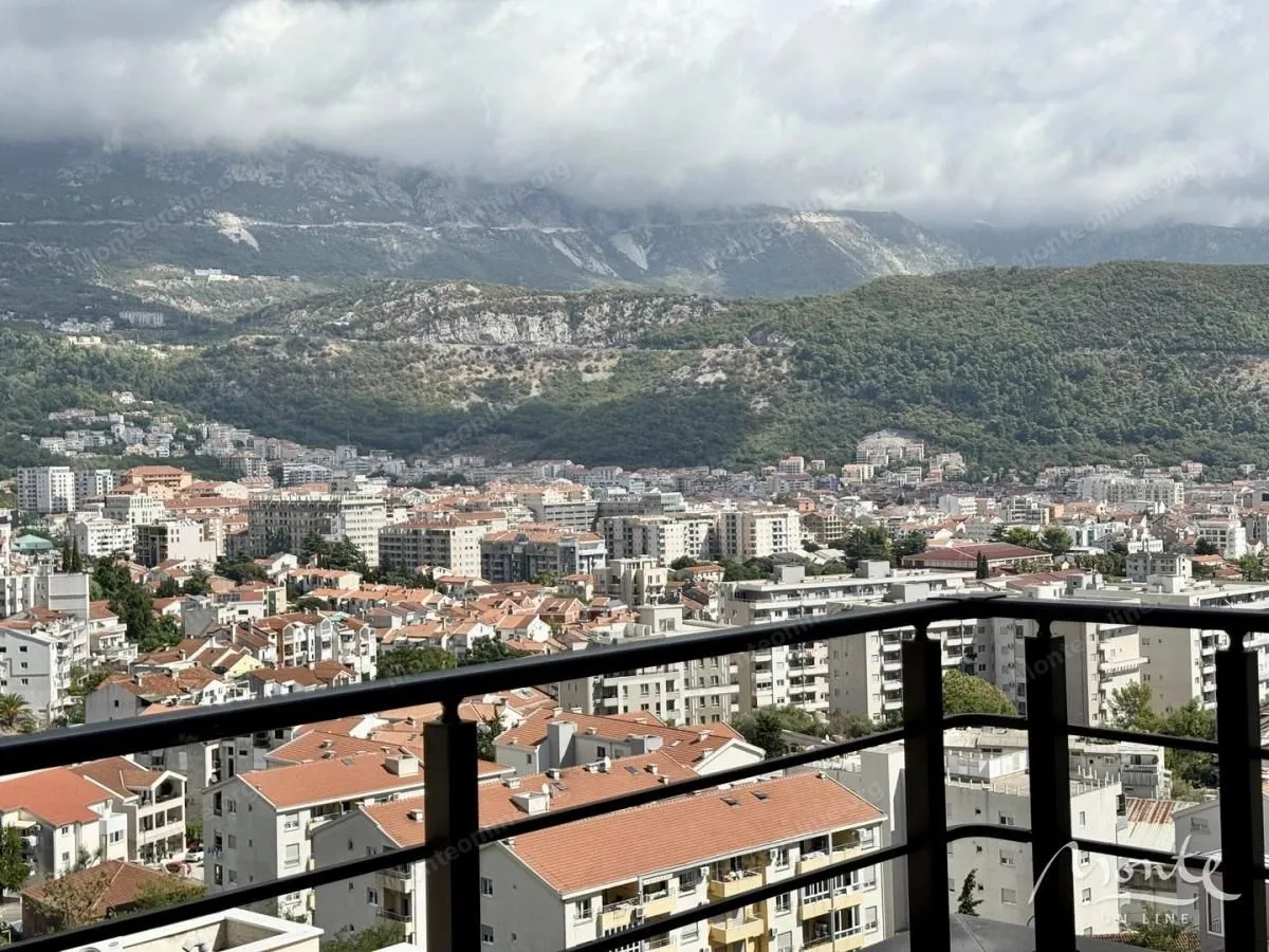 Pogled sa terase na grad i planine u pozadini.