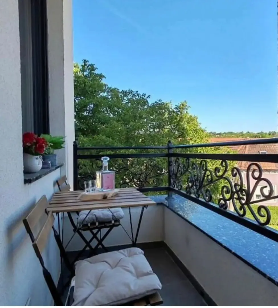 Namešten balkon sa stolom, stolicama i pogledom na zelenilo.