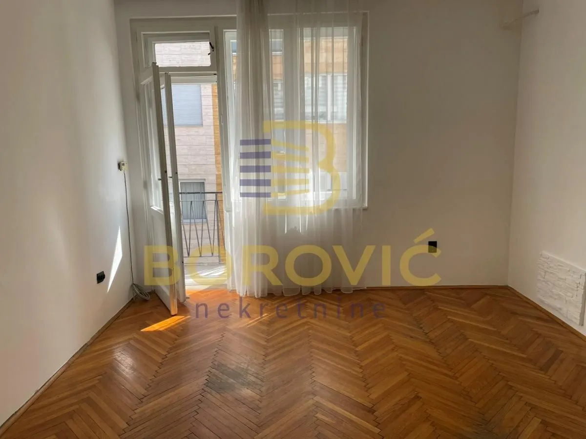 Empty room with hardwood parquet flooring and access to a balcony.