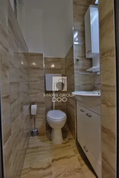 Manje kupatilo obloženo bež pločicama sa toaletom i umivaonikom. - image 17