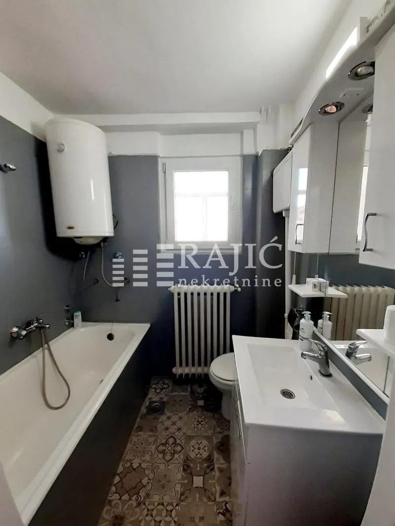 Small bathroom with a bathtub, sink, toilet, and water heater.