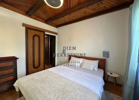 Furnished bedroom with a double bed, wooden ceiling beams, and sliding doors. - image 10