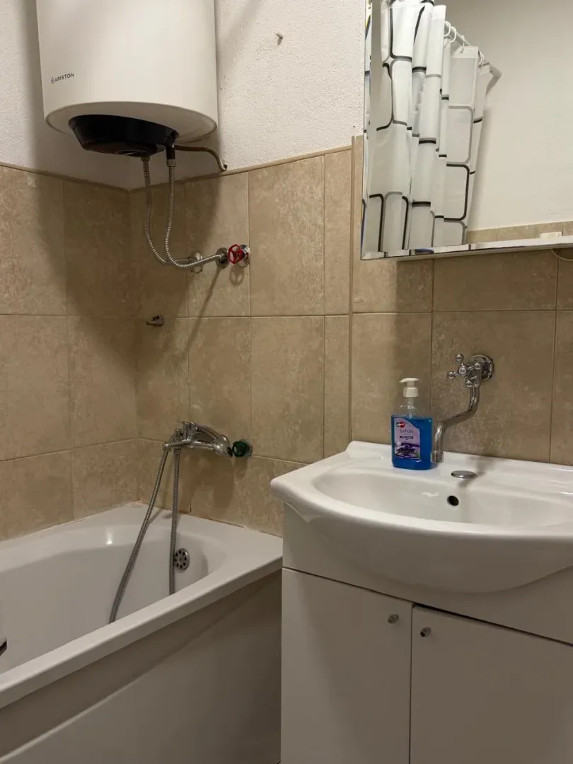 Small bathroom with a bathtub, sink, and water heater.