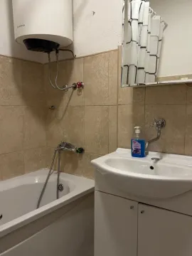 Small bathroom with a bathtub, sink, and water heater. - image 12