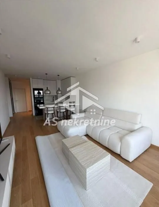 Living room with a sofa and dining area in the back.