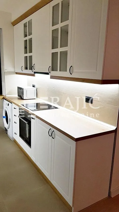 Modern white kitchen with built-in appliances and a countertop.