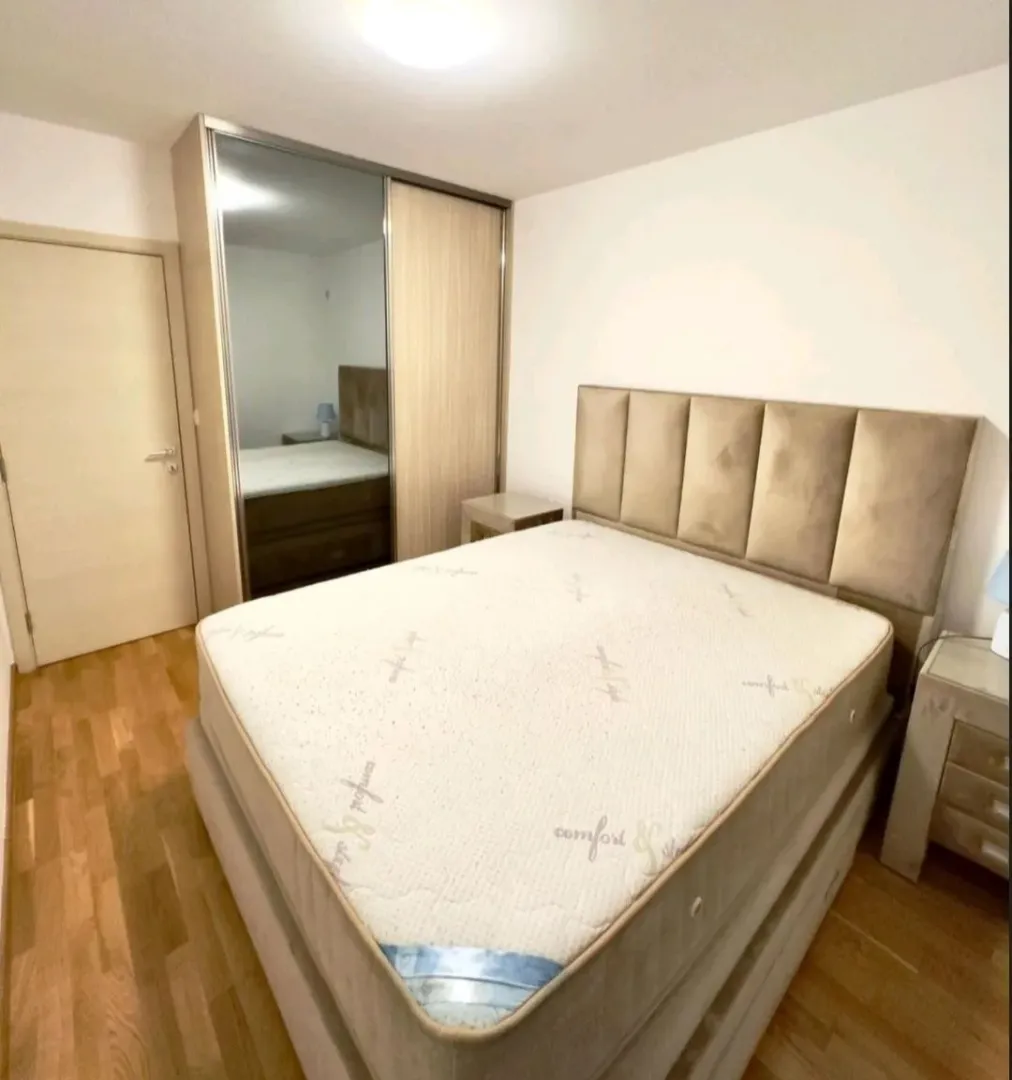 Furnished bedroom with a double bed and a mirrored built-in wardrobe.
