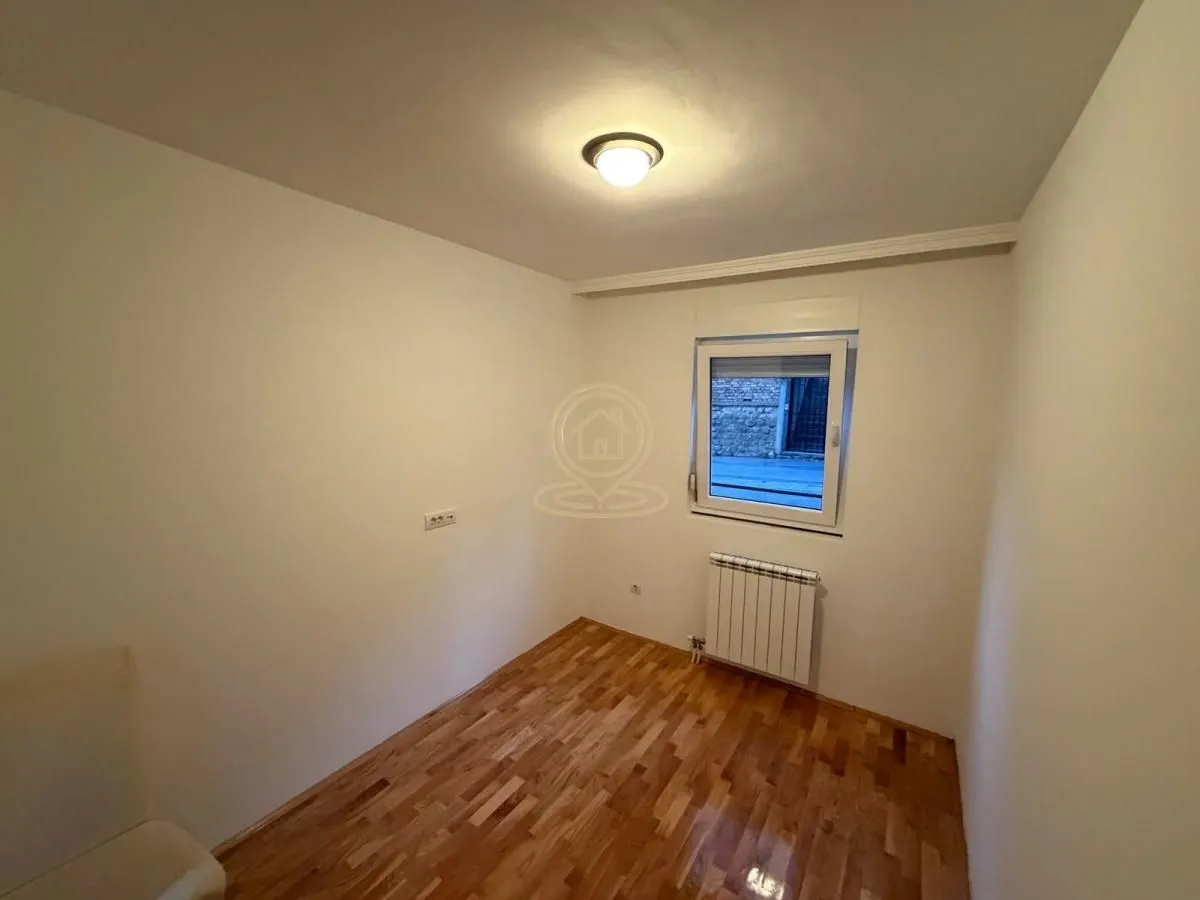 Prazna soba sa parketom i jednim prozorom.
