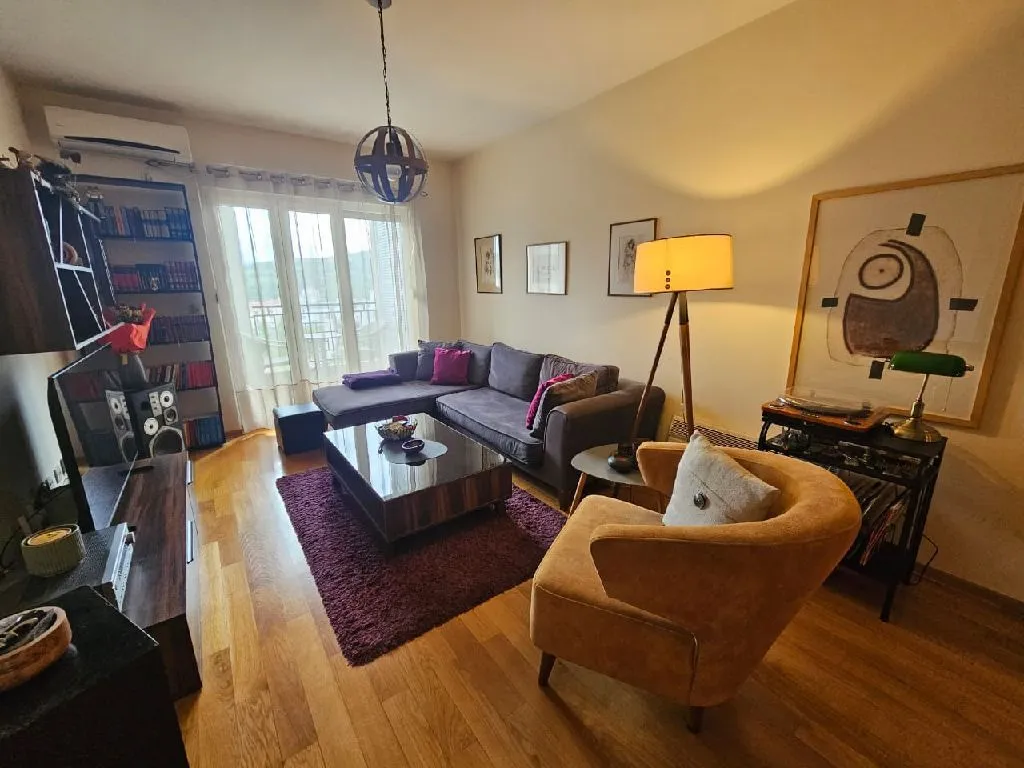 Furnished living room with a sofa, armchair, and bookshelf.