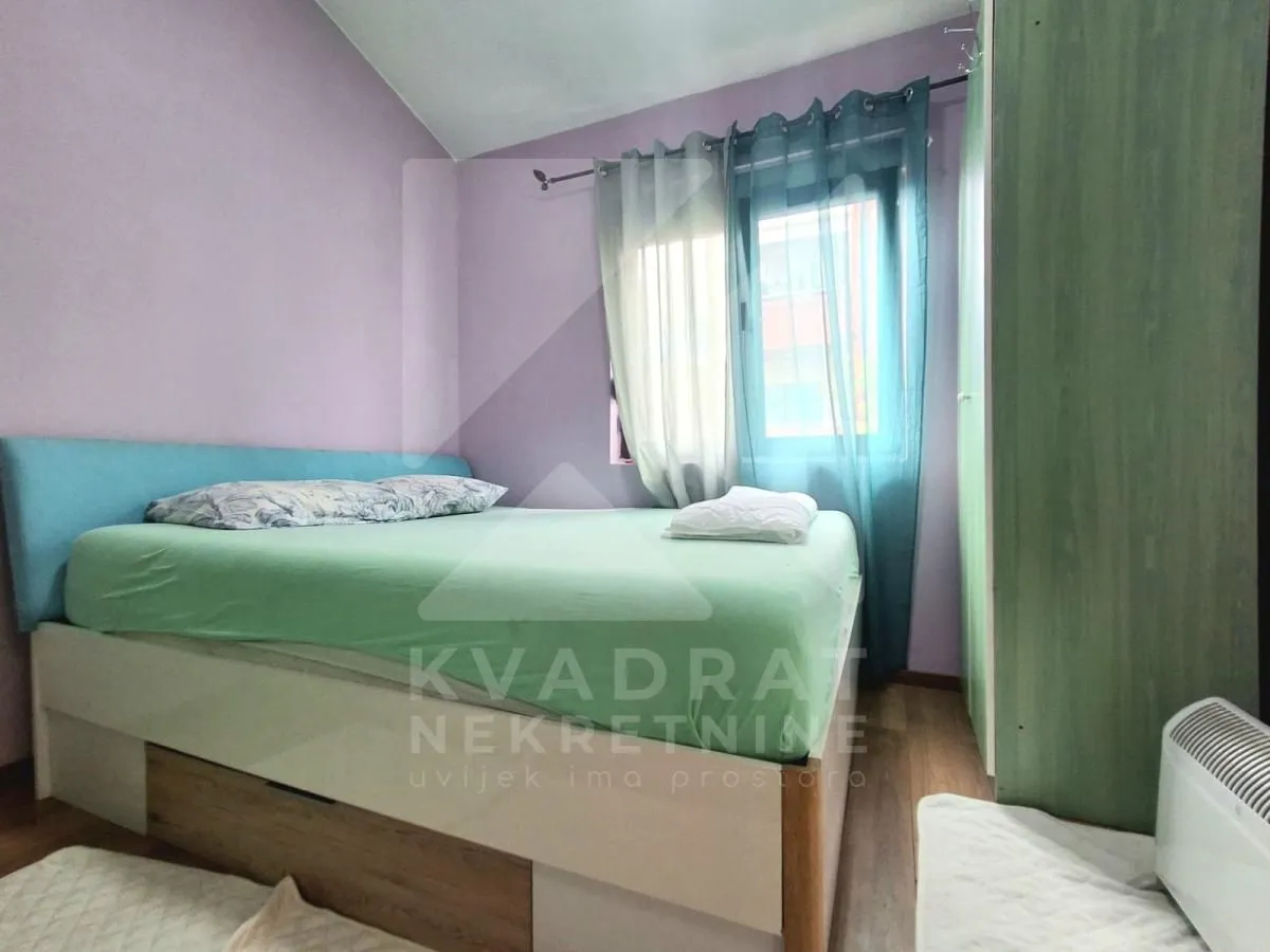Namještena spavaća soba sa bračnim krevetom i prozorom.