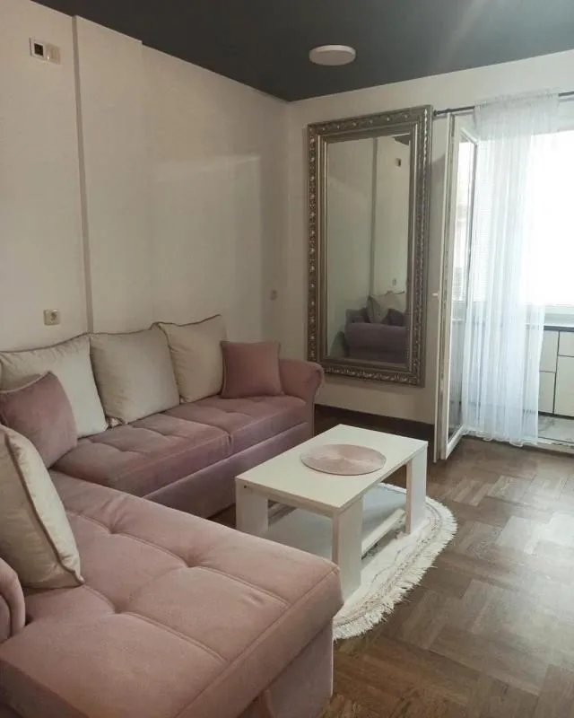 Living room with a pink sofa set, coffee table, and a large wall mirror.