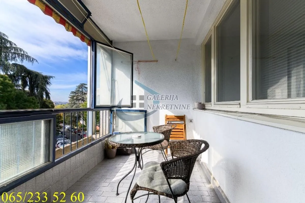 Zastakljeni balkon sa garniturom za sedenje i pogledom na okolinu.
