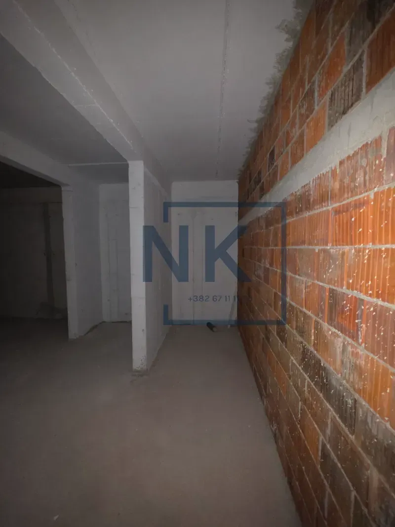 View of an unfurnished space in rough construction phase with an exposed brick wall.