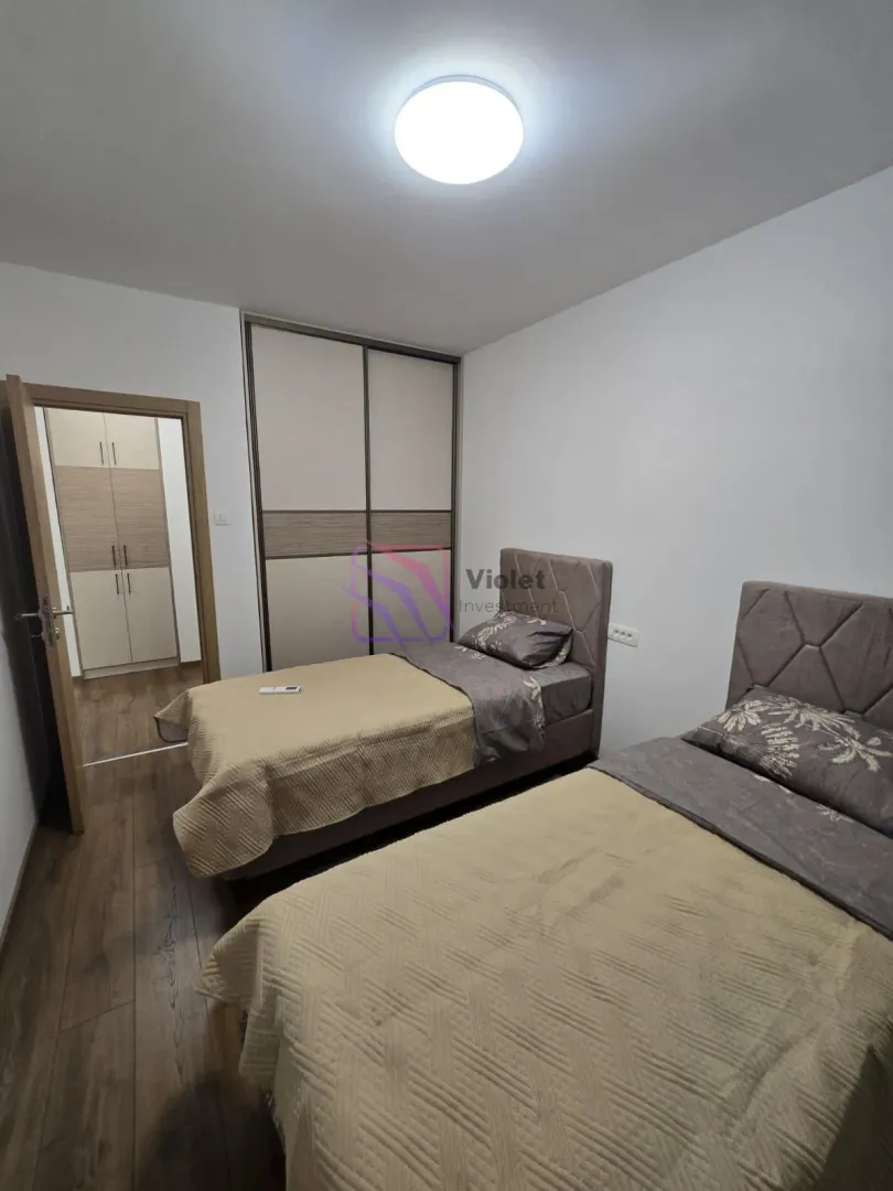 Spavaća soba sa dva singl kreveta i ugradnim ormarom.