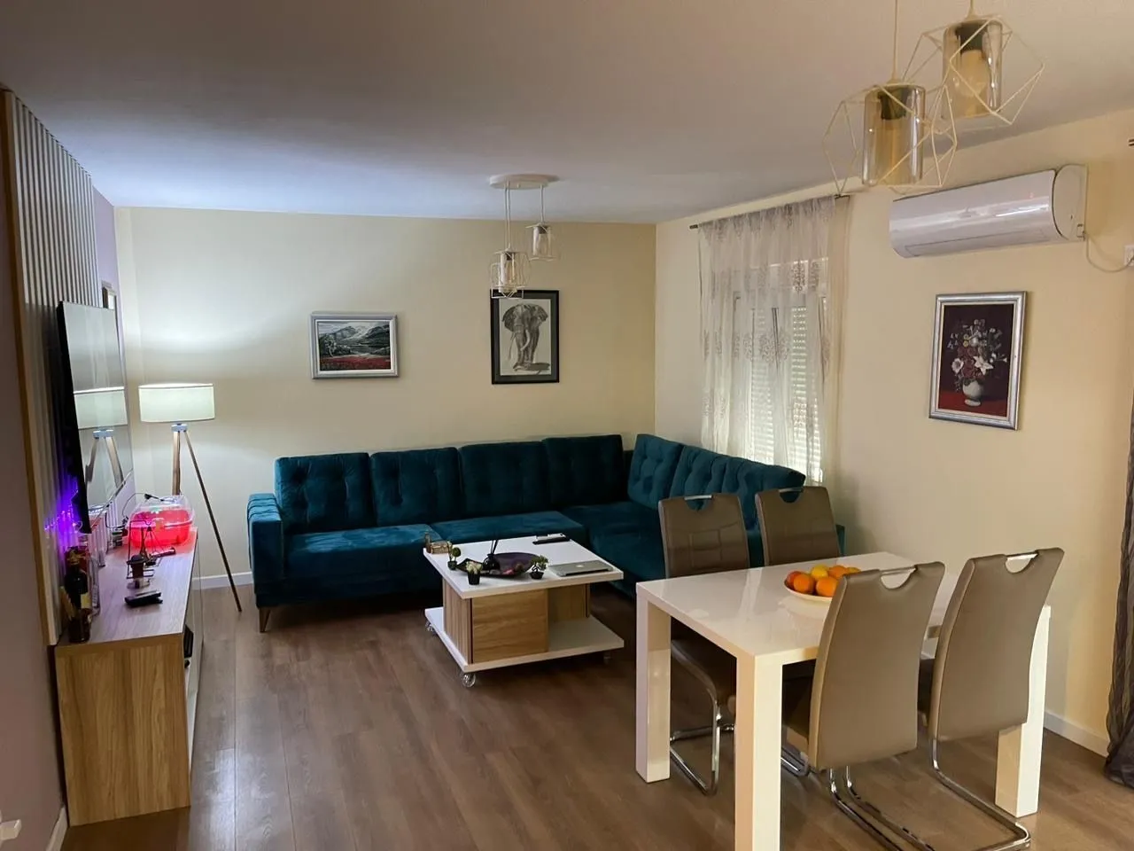 Living room with a blue corner sofa and a dining table.