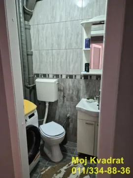 Manje kupatilo sa toaletom, umivaonikom, veš mašinom i pločicama. - image 7