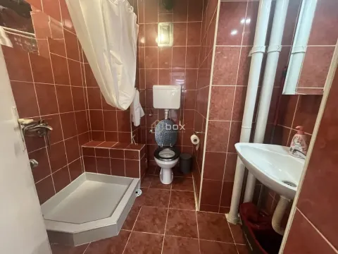 Smaller bathroom with a shower cabin lined with red tiles. - image 11