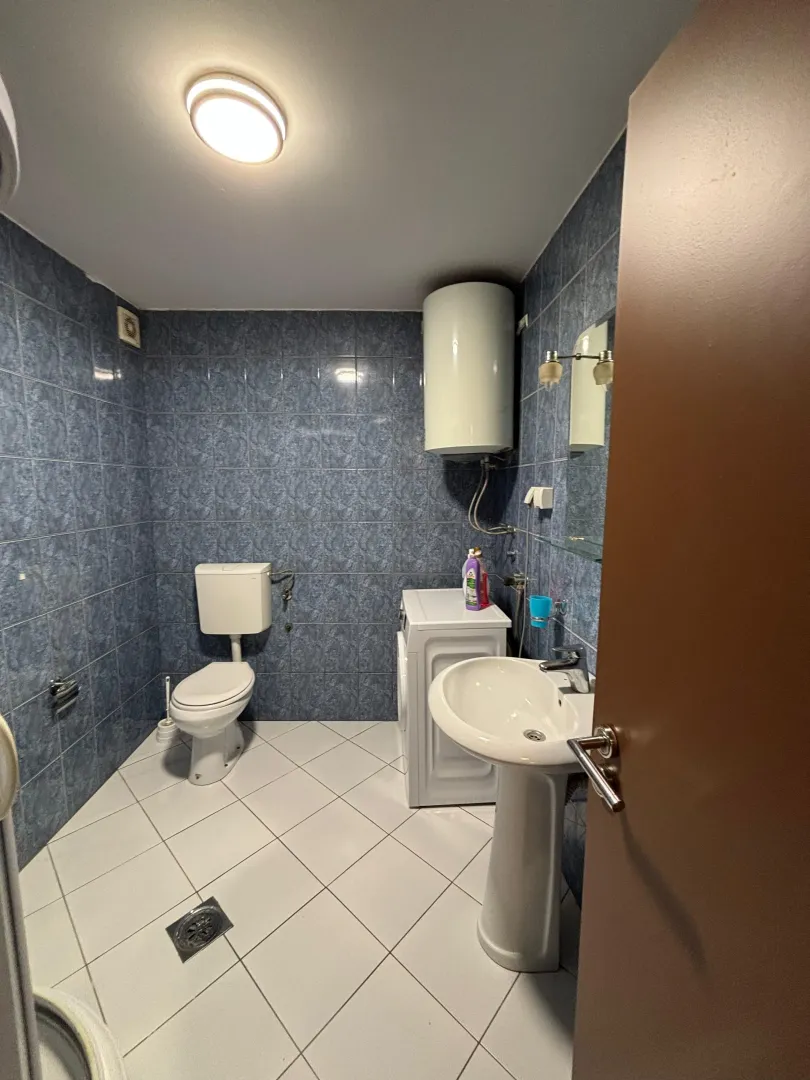 Small bathroom with blue tiles, washbasin, and toilet.