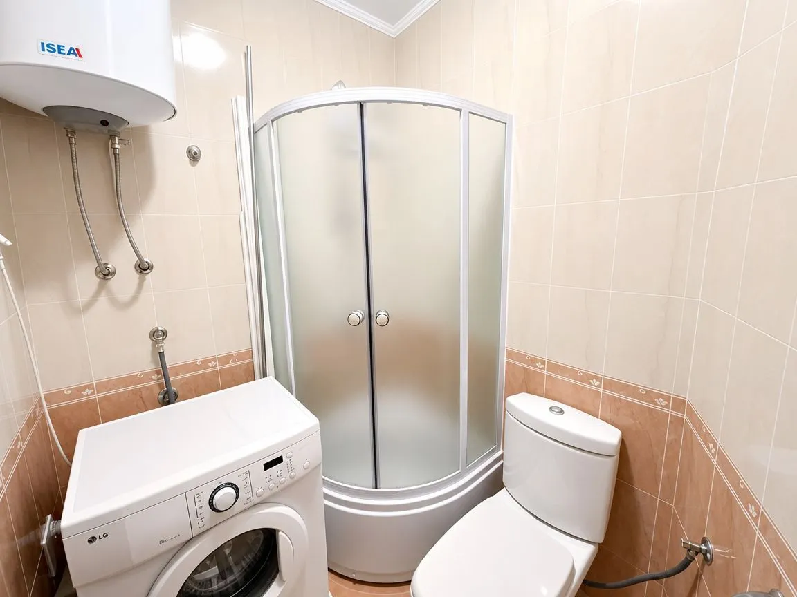 Bathroom equipped with a shower cabin, toilet, washing machine, and water heater.