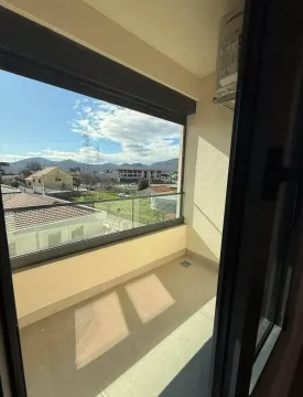 Manji zatvoreni balkon sa staklenom ogradom i pogledom na naselje. - image 8