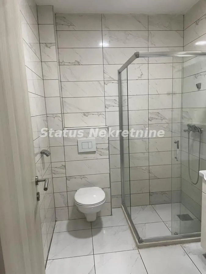 Moderno kupatilo sa tuš kabinom i ugradnom šoljom.