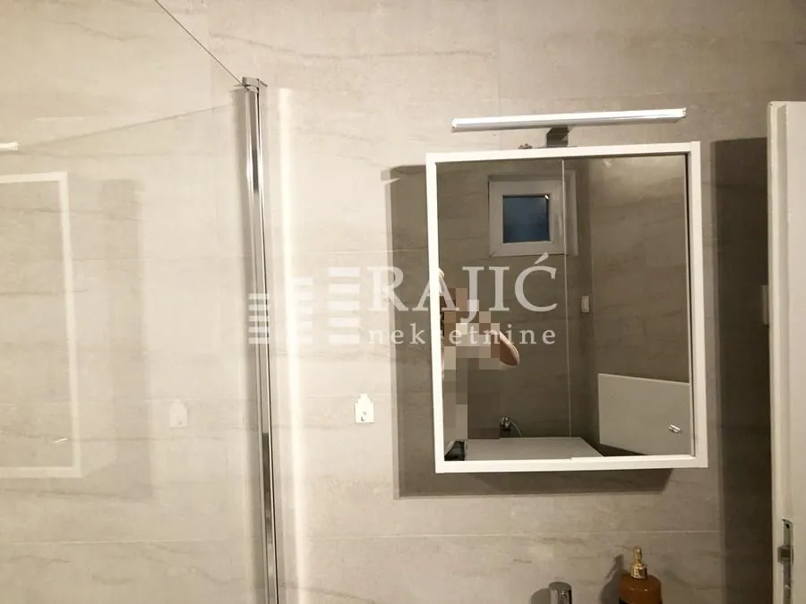 Modernly equipped bathroom with a shower cabin and a mirror.