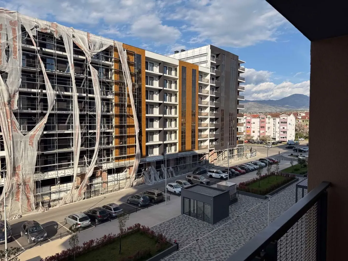 View from the terrace overlooking surrounding buildings, parking lot, and distant mountains.