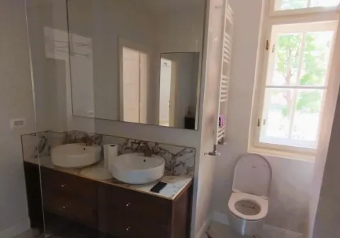 Modern bathroom with double sinks, large mirror, and toilet. - image 11