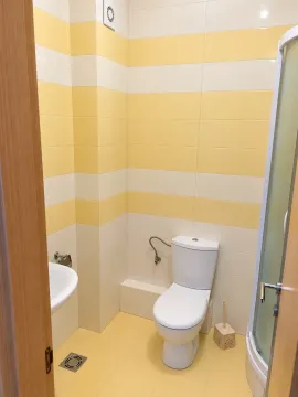 Manje kupatilo sa žuto-bijelim pločicama, wc šoljom, umivaonikom i tuš kabinom. - image 6