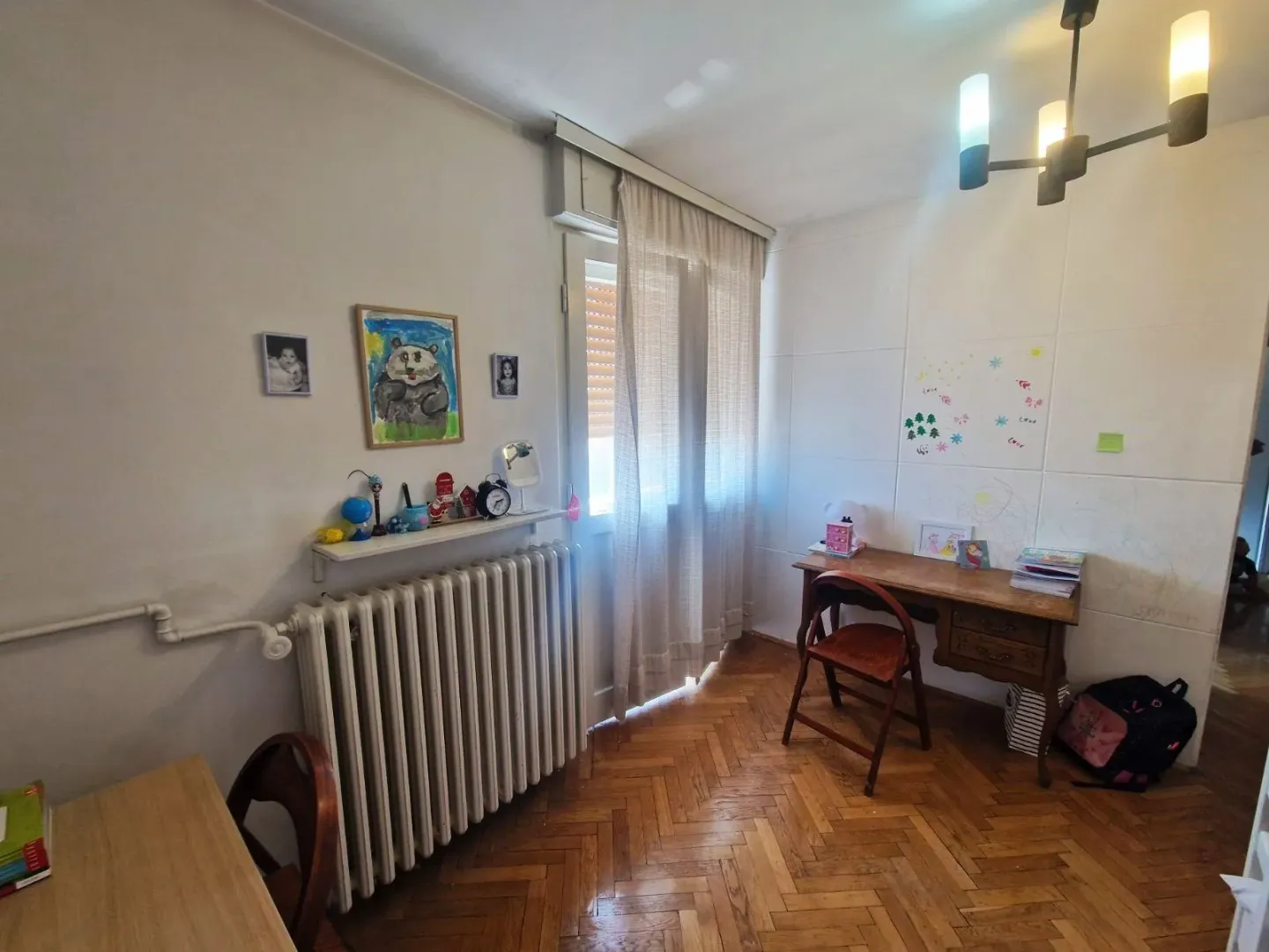 Dečja soba sa radnim stolom, prozorom i drvenim podom.
