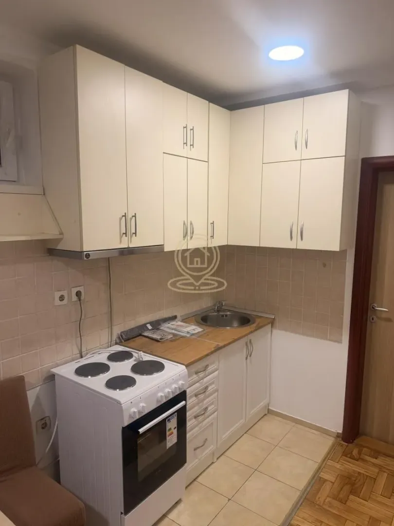 Small kitchen with white cabinetry, stove, and sink.