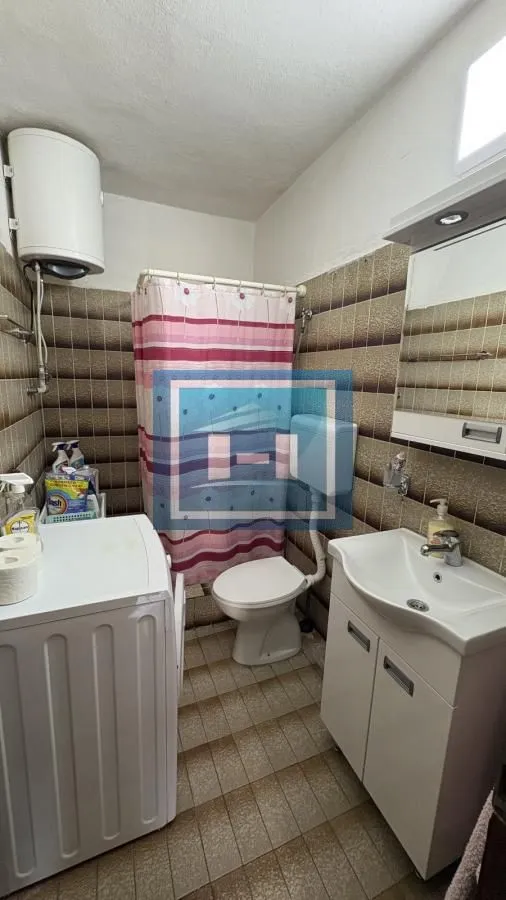 Kupatilo opremljeno umivaonikom, WC šoljom, tuš kabinom i mašinom za veš.