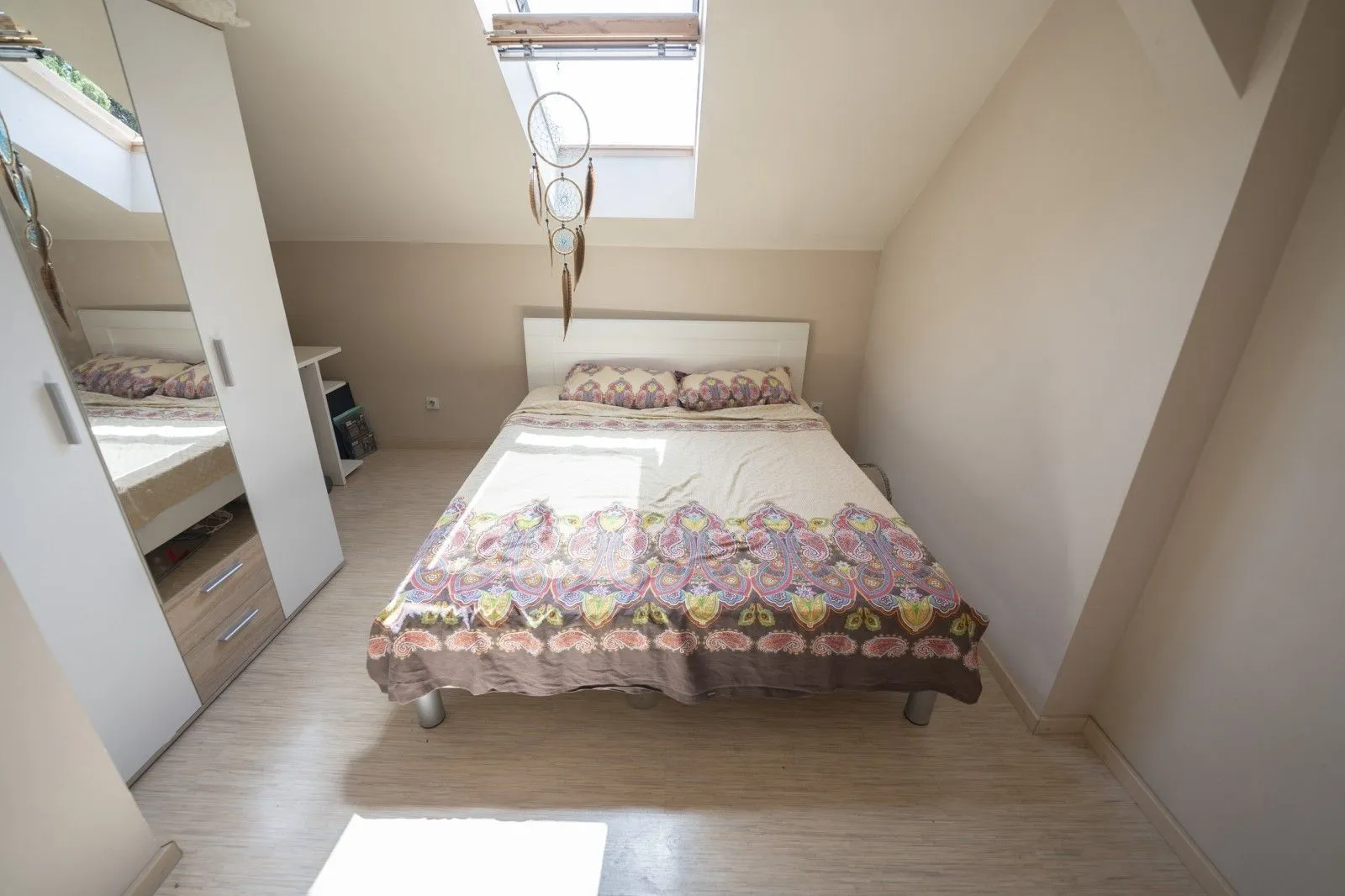 Bright attic bedroom with a double bed and a white wardrobe.