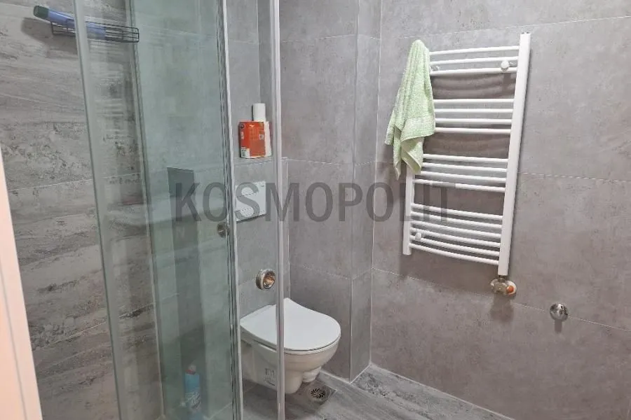 Moderno opremljeno kupatilo sa tuš kabinom i radijatorom za sušenje peškira.