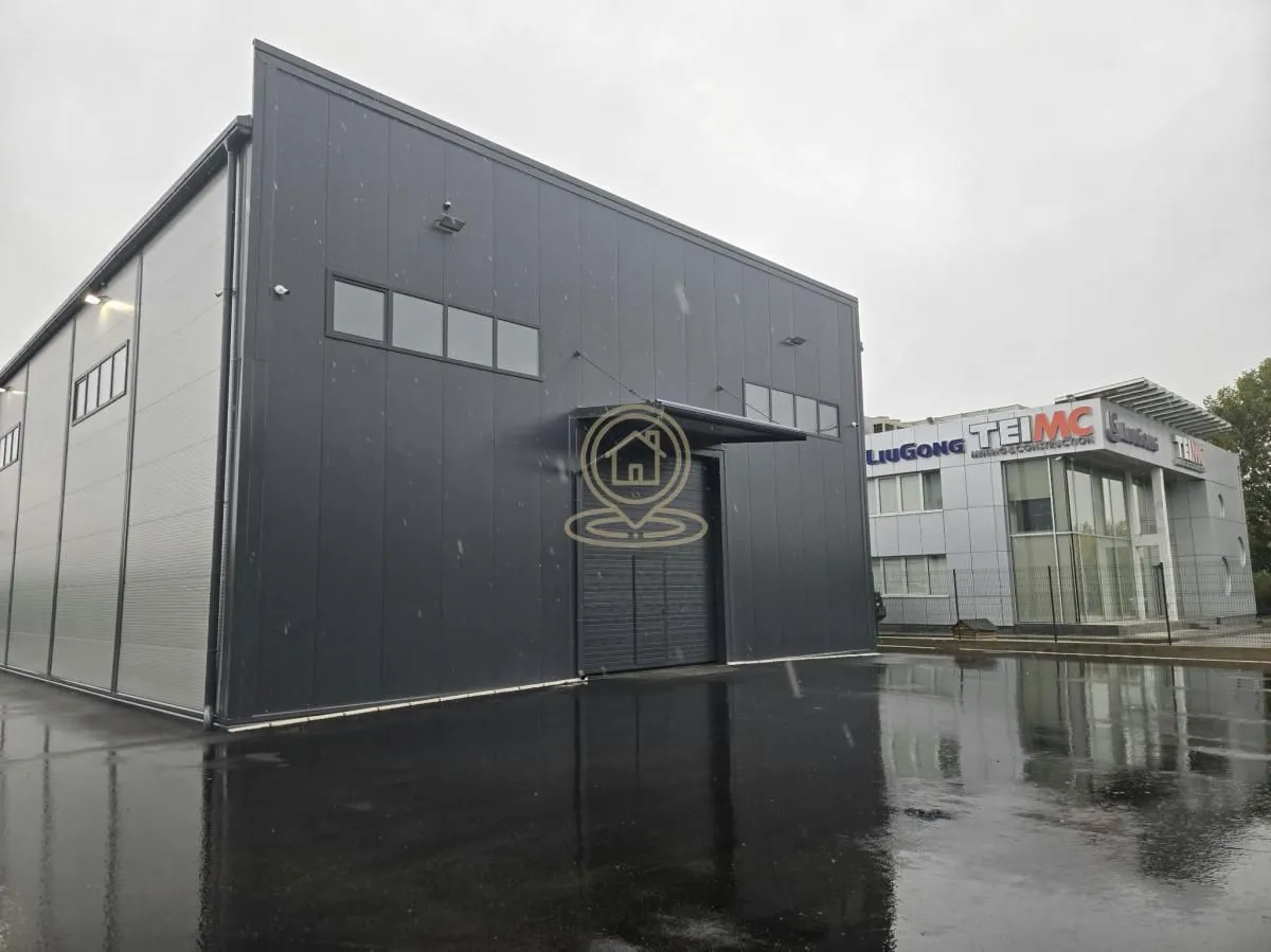 Exterior view of a modern industrial warehouse with an asphalted courtyard.
