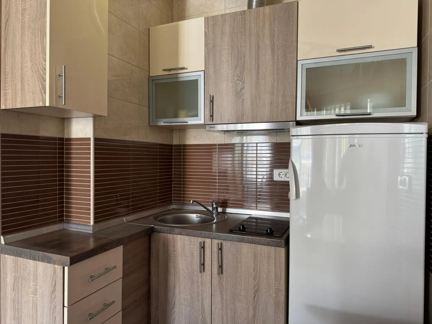 Small kitchen with a sink, built-in cooktop, and refrigerator.