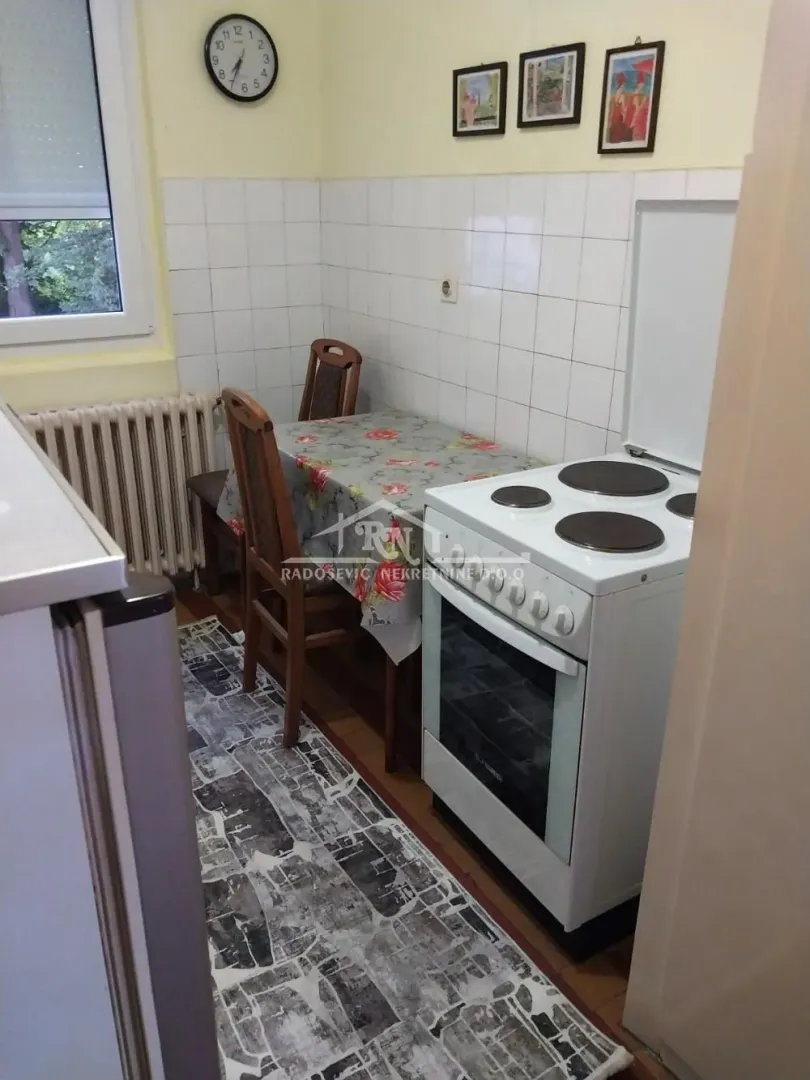 Manja kuhinja sa šporetom, trpezarijskim stolom i stolicama.