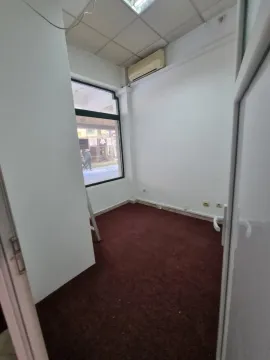 An empty room with dark carpeting and a window facing the street. - image 4