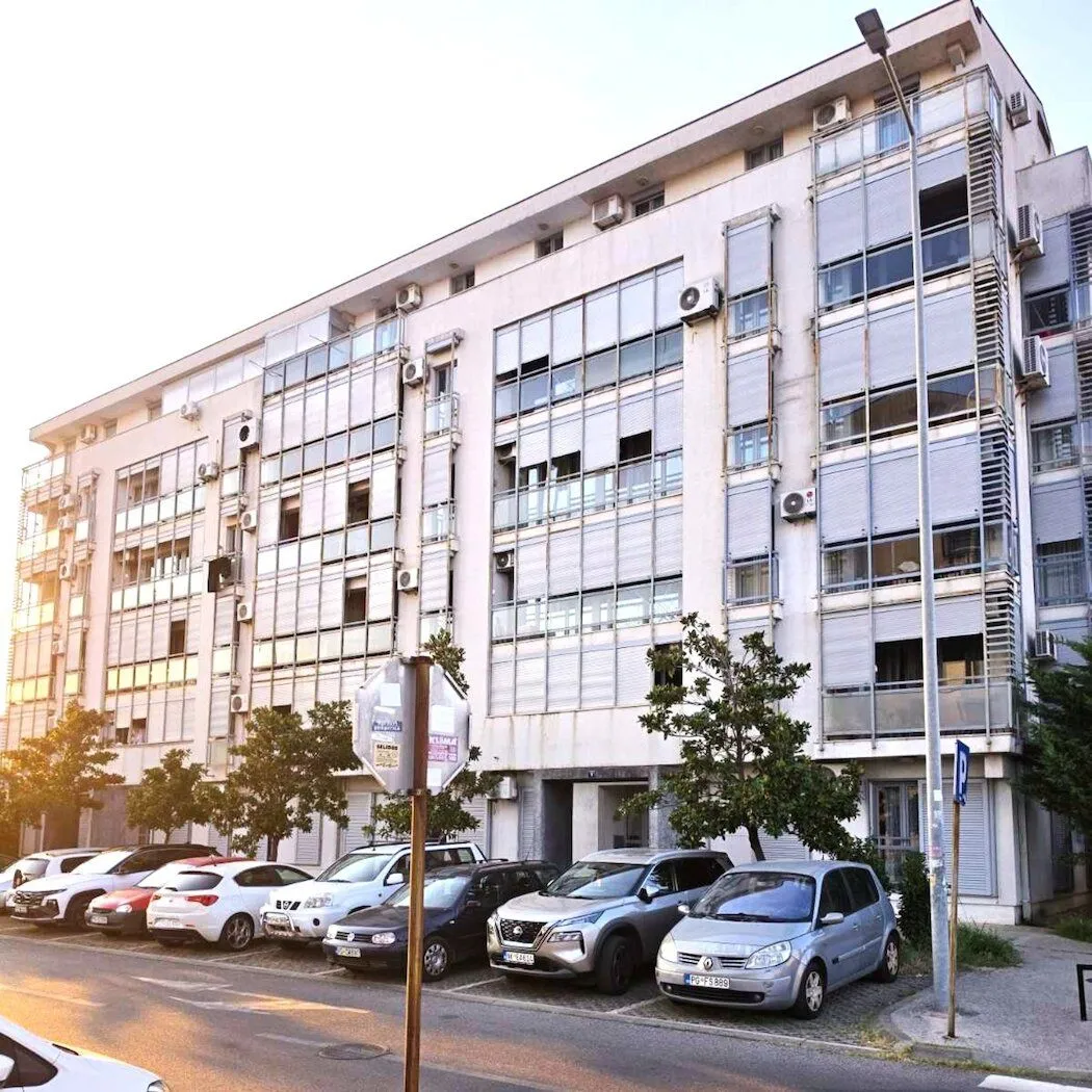 Exterior view of an apartment building with parking in front.