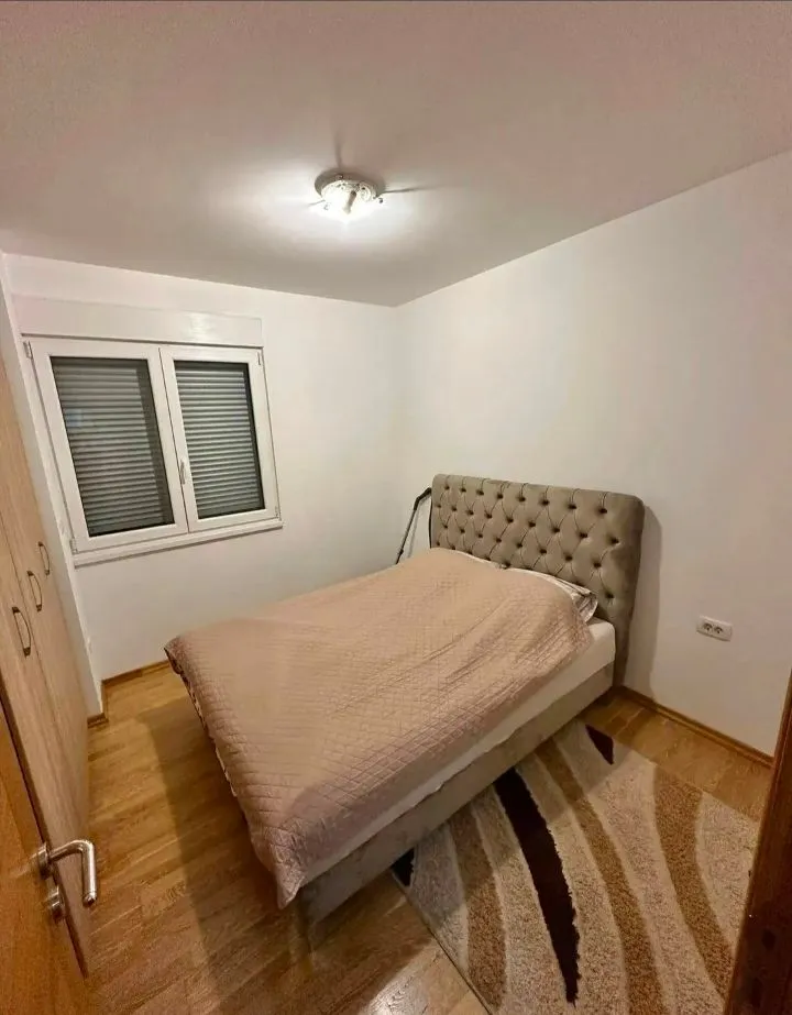 Spavaća soba sa bračnim krevetom, plakarom i prozorom.