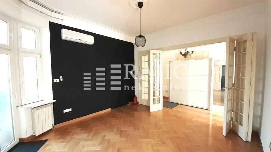 Spacious living room with parquet flooring and a black accent wall.