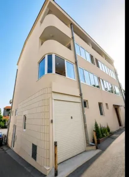 Pogled na spoljašnost višestambene zgrade sa garažnim vratima i terasama. - image 8