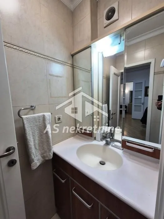 Bathroom with a vanity sink, cabinet, and large mirror.
