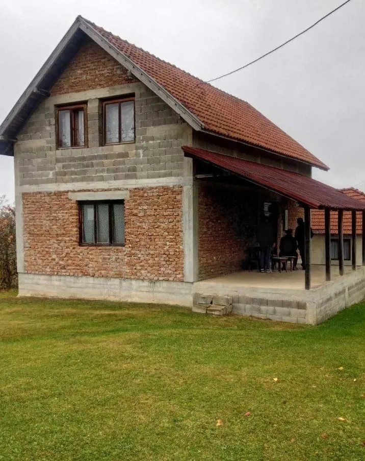 Eksterijer kuće sa pokrivenom terasom i travnjakom u dvorištu.
