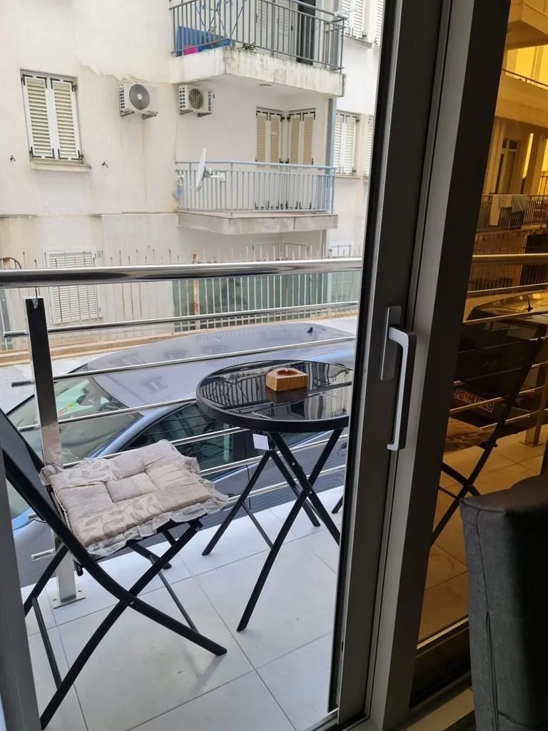 Manji namješten balkon sa stolom i stolicama sa pogledom na ulicu.