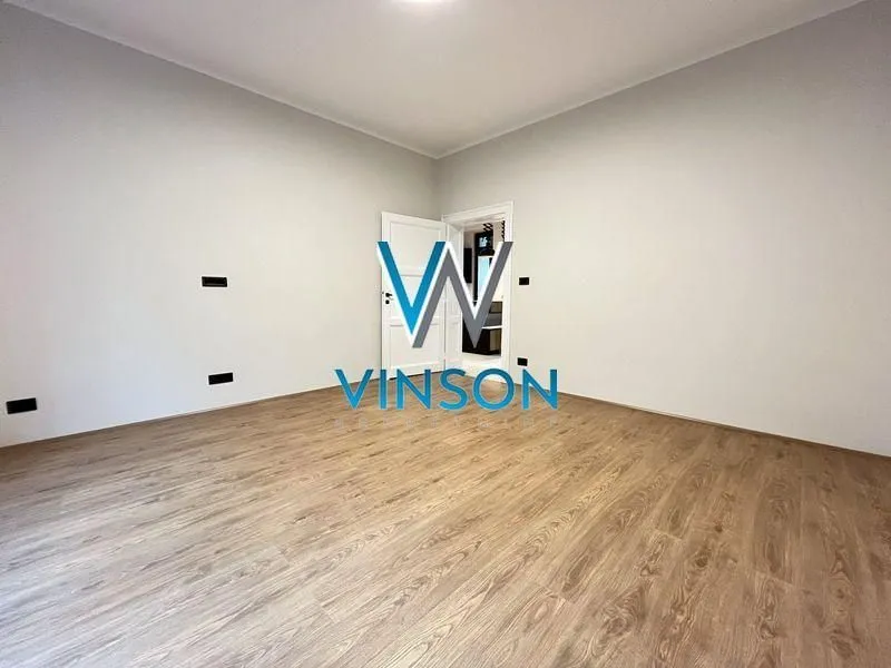 Empty room with laminate flooring and white walls.