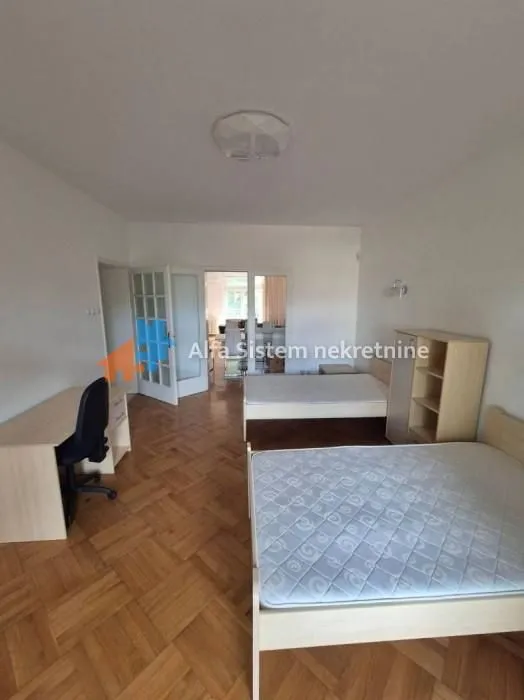 Spacious bedroom with two single beds and a desk.